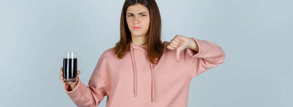 woman with drink doing thumbs down